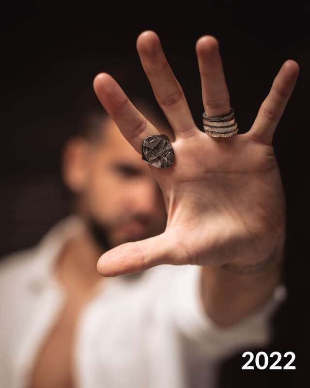 Photo d'un homme qui porte à ses doigts des alliances, bijoux de créateur. 